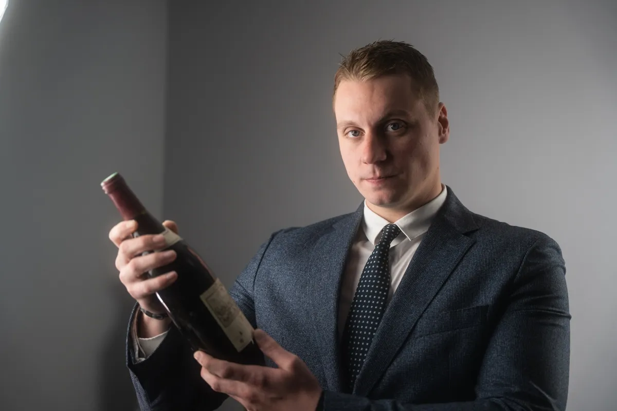 Florian, expert de l'équipe, présente une bouteille de vin de collection à estimer