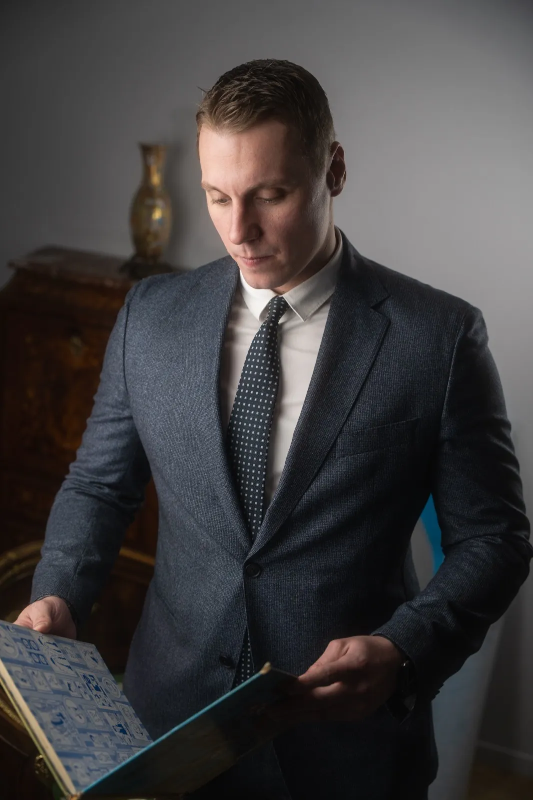 Florian, expert de l'équipe, feuillette un livre ancien près d'une commode marquetée
